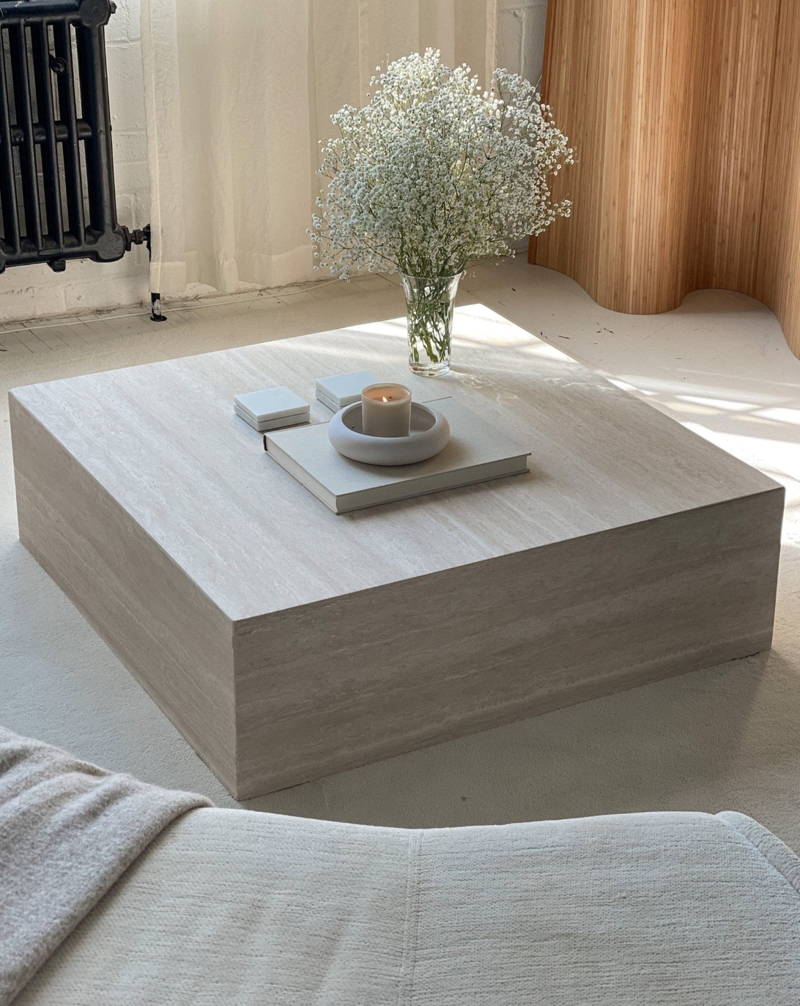 Slab square marble plinth coffee table styled in living room — low profile stone centrepiece