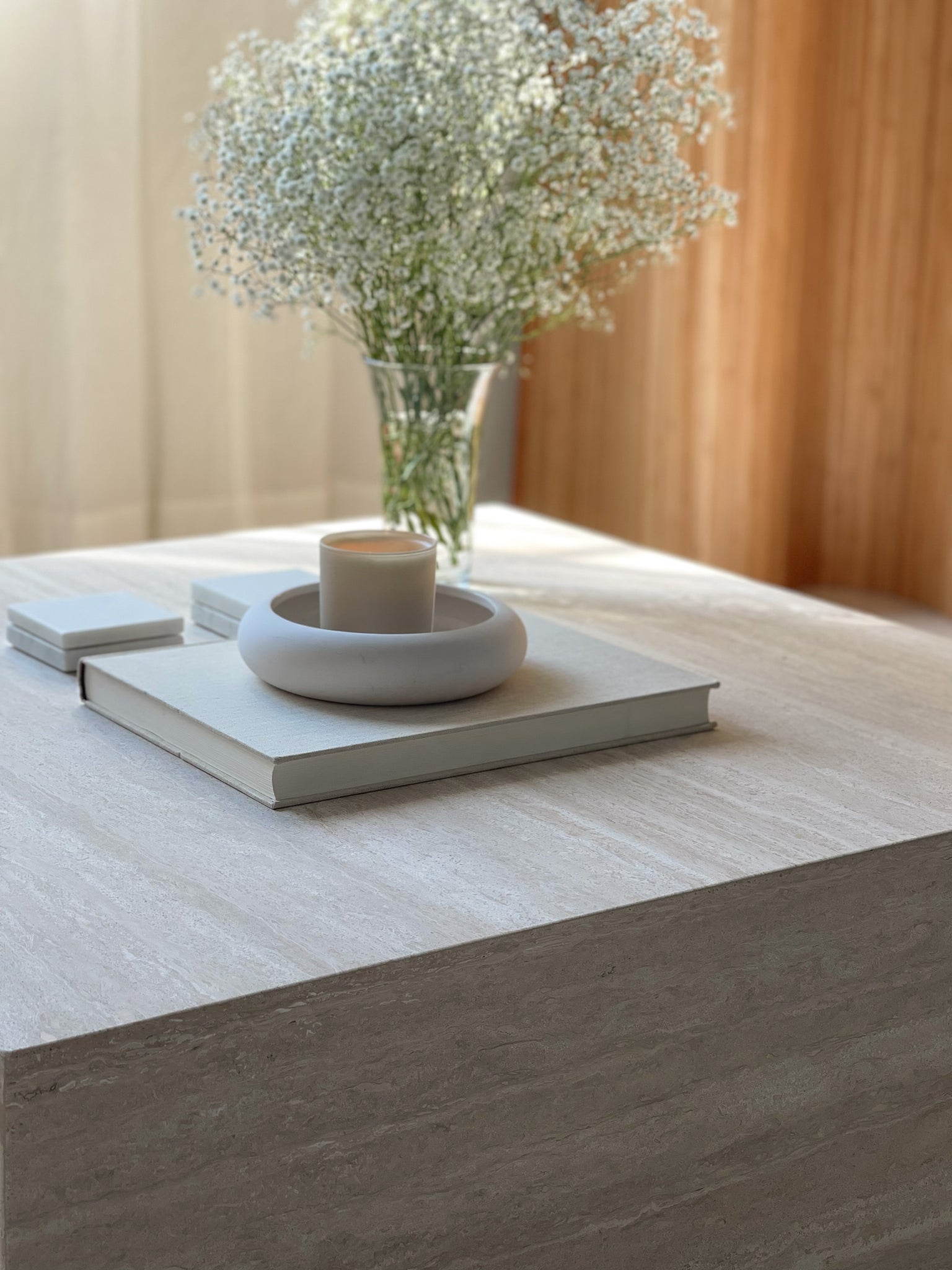 Slab square marble plinth coffee table styled in living room — low profile stone centrepiece