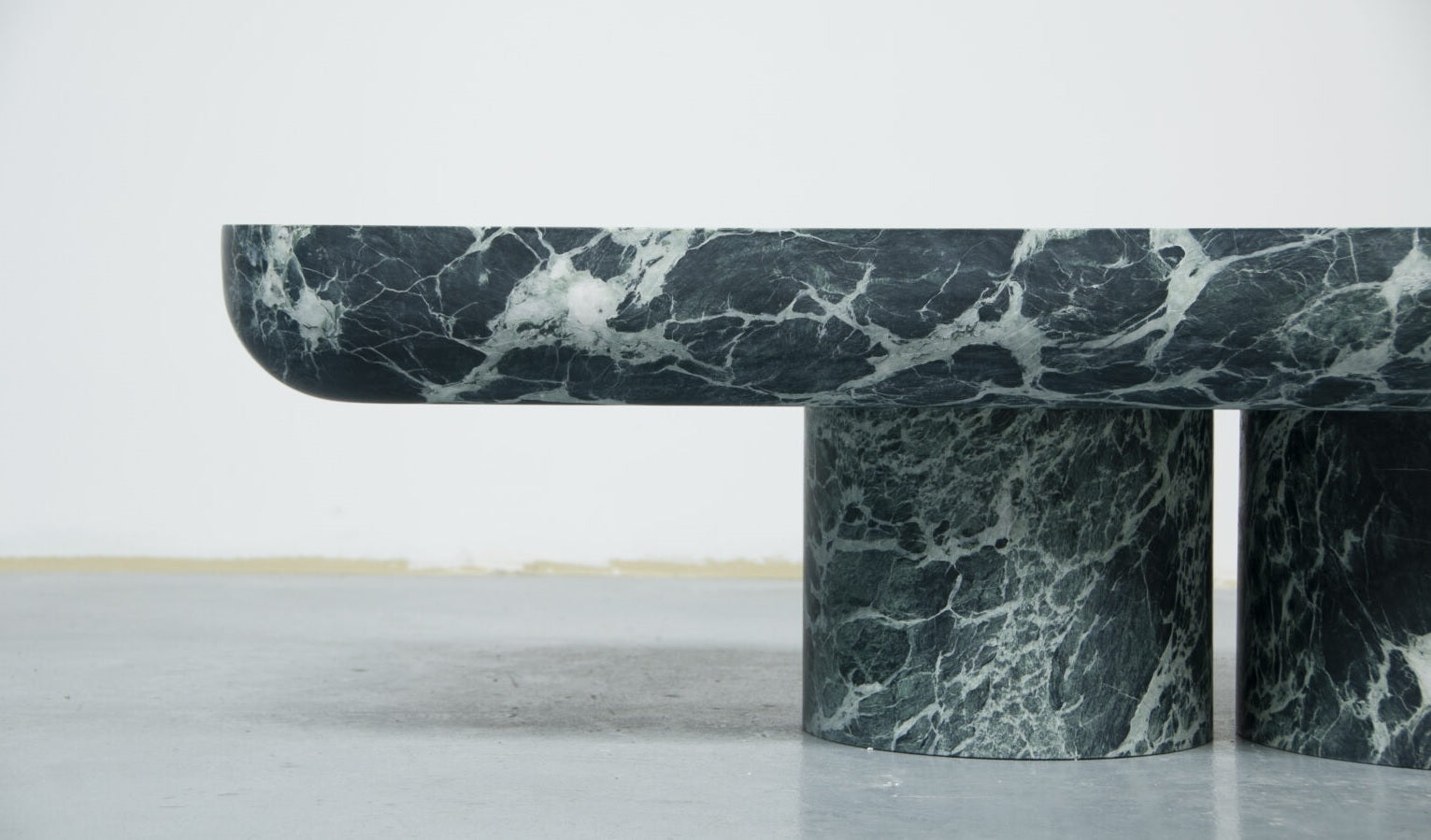Marble coffee table with a dark green and white pattern on a light gray floor.